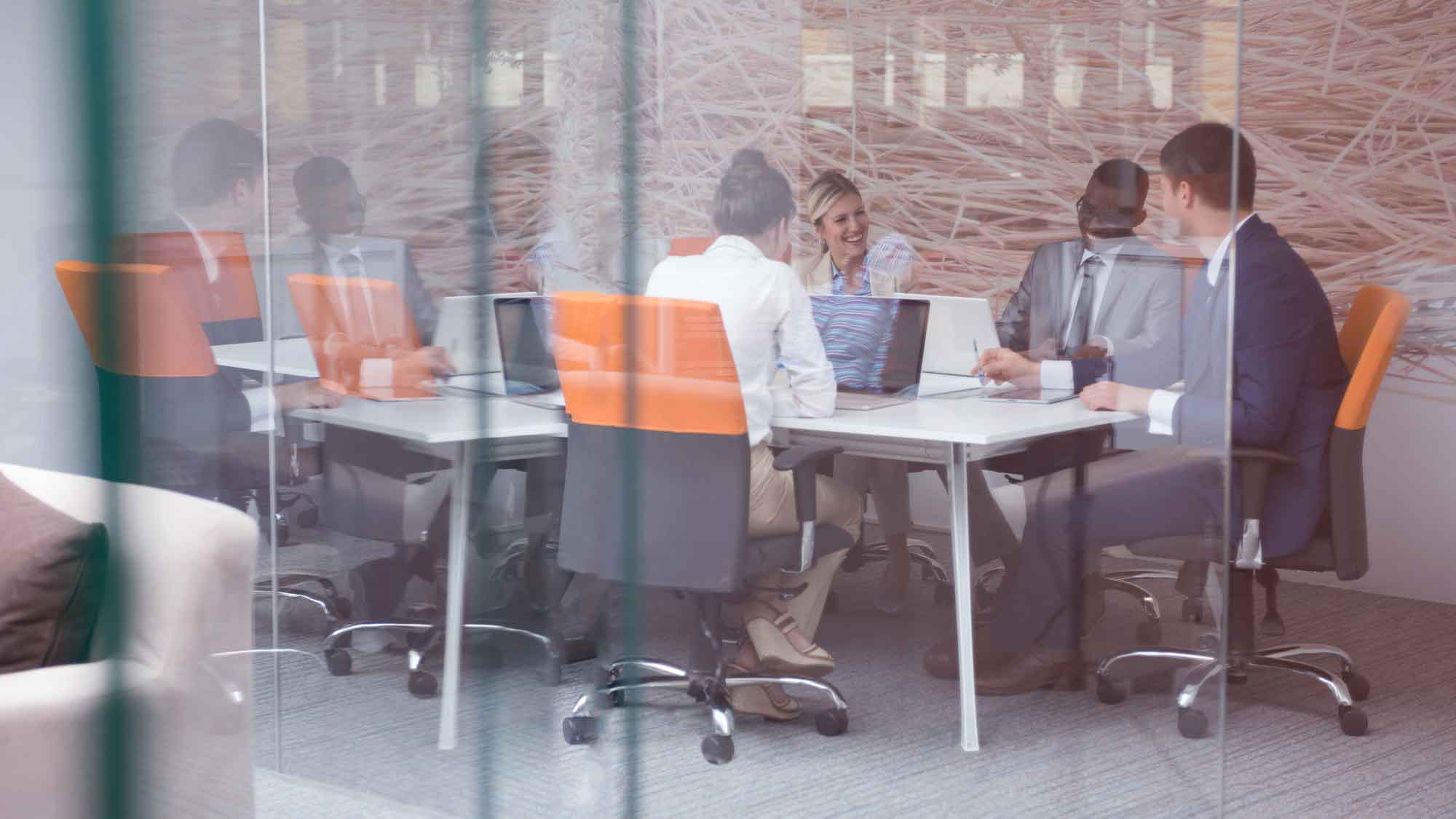 Group of people in an office in front of glass