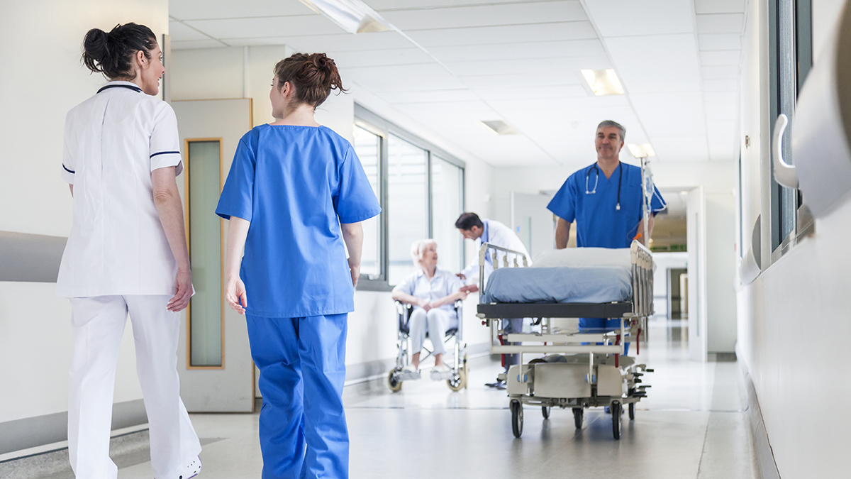 Male nurse pushing stretcher in hospital corridor
